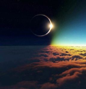 A solar eclipse is seen from above the clouds.